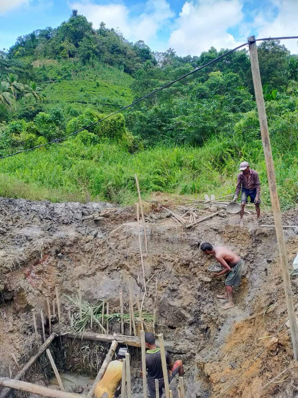 Three miners working an open gem pit cut into a hillside, timber shoring along the walls